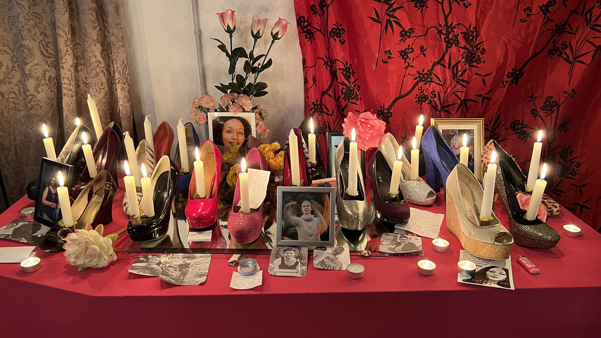 A colourful altar with sacred objects, framed photographs and high heel candle holders